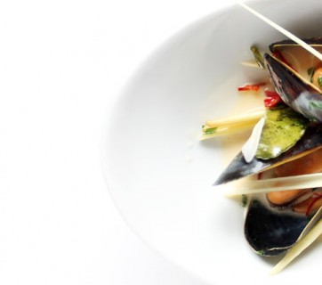 Mussels with thai flavors, from above. Part of a small bowl on white background